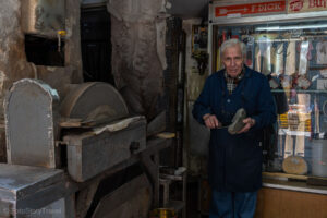 Starszy pan ostrzy duży nóż o kamień